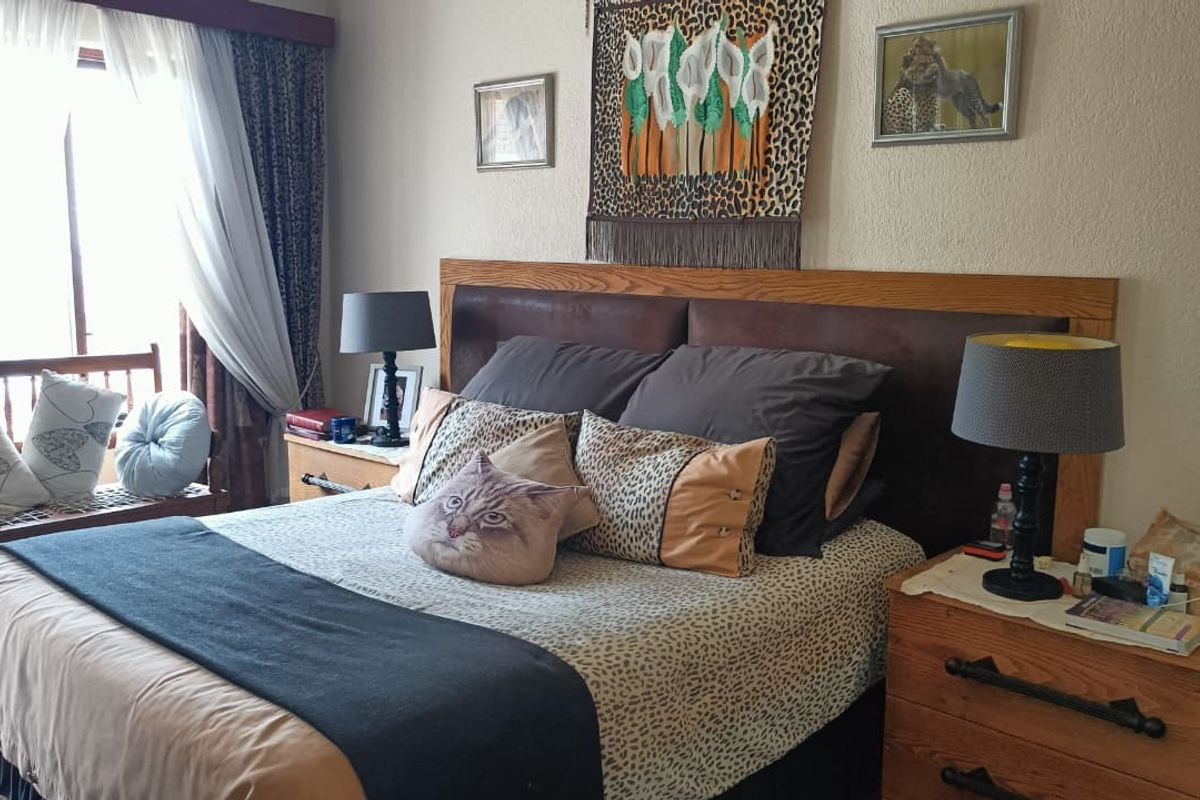 A cozy bedroom featuring a large built-in headboard and natural light from the adjacent window area.