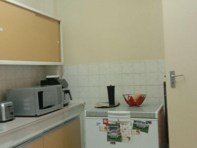 A functional kitchen area featuring built-in cabinetry, tiled splashbacks, and laminate countertops, providing a practical workspace for daily food preparation.