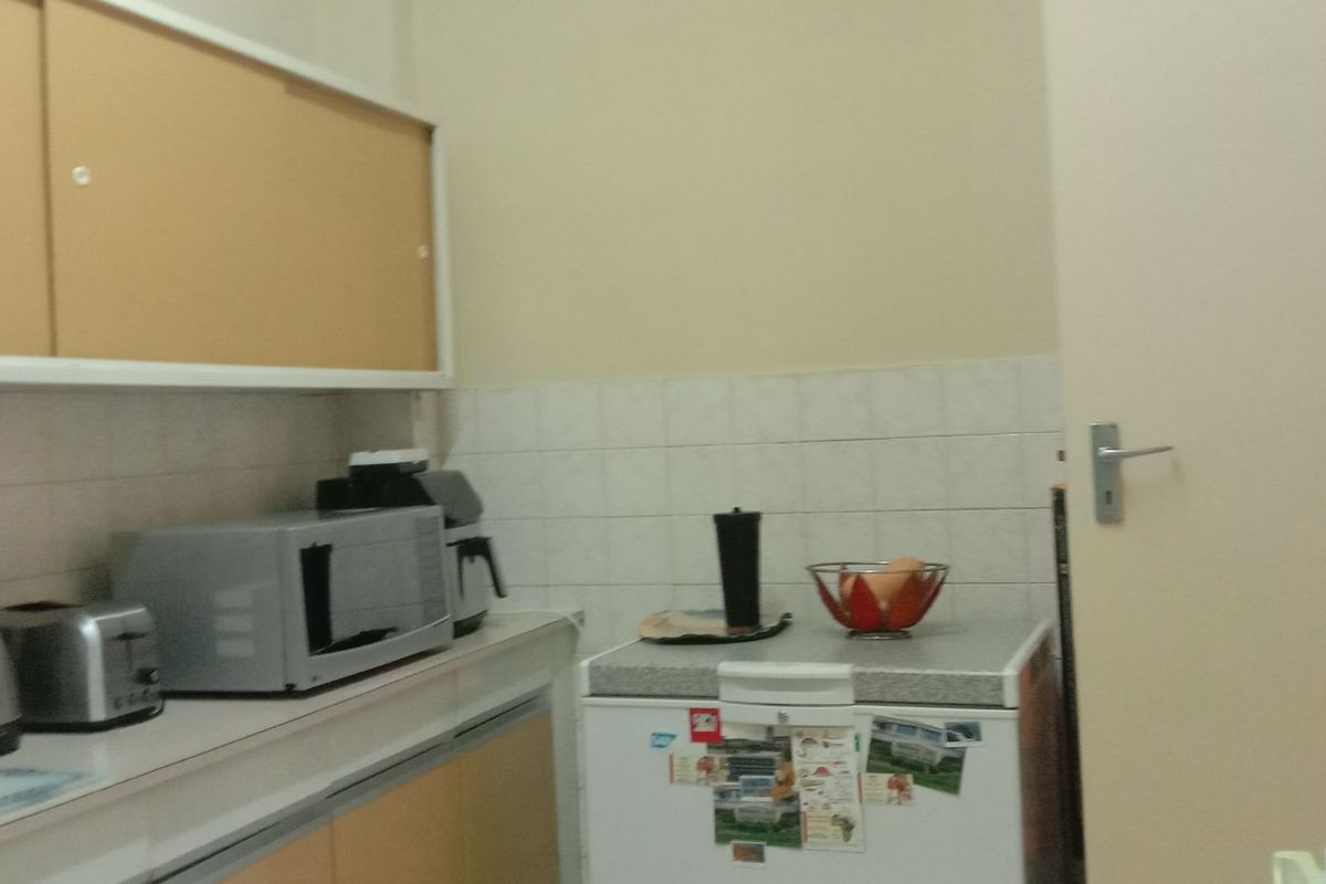 A functional kitchen area featuring built-in cabinetry, tiled splashbacks, and laminate countertops, providing a practical workspace for daily food preparation.
