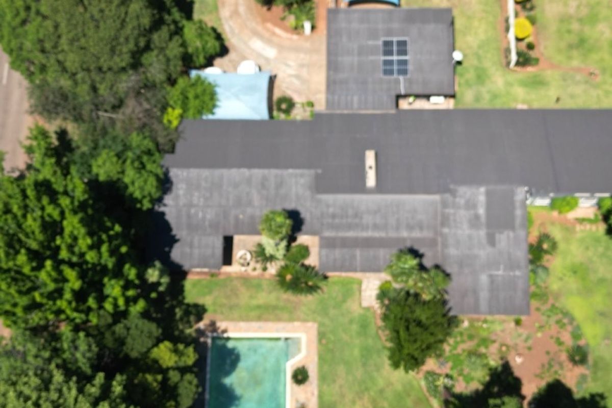 Aerial view of the property showing the roof structure, swimming pool, and surrounding garden area.