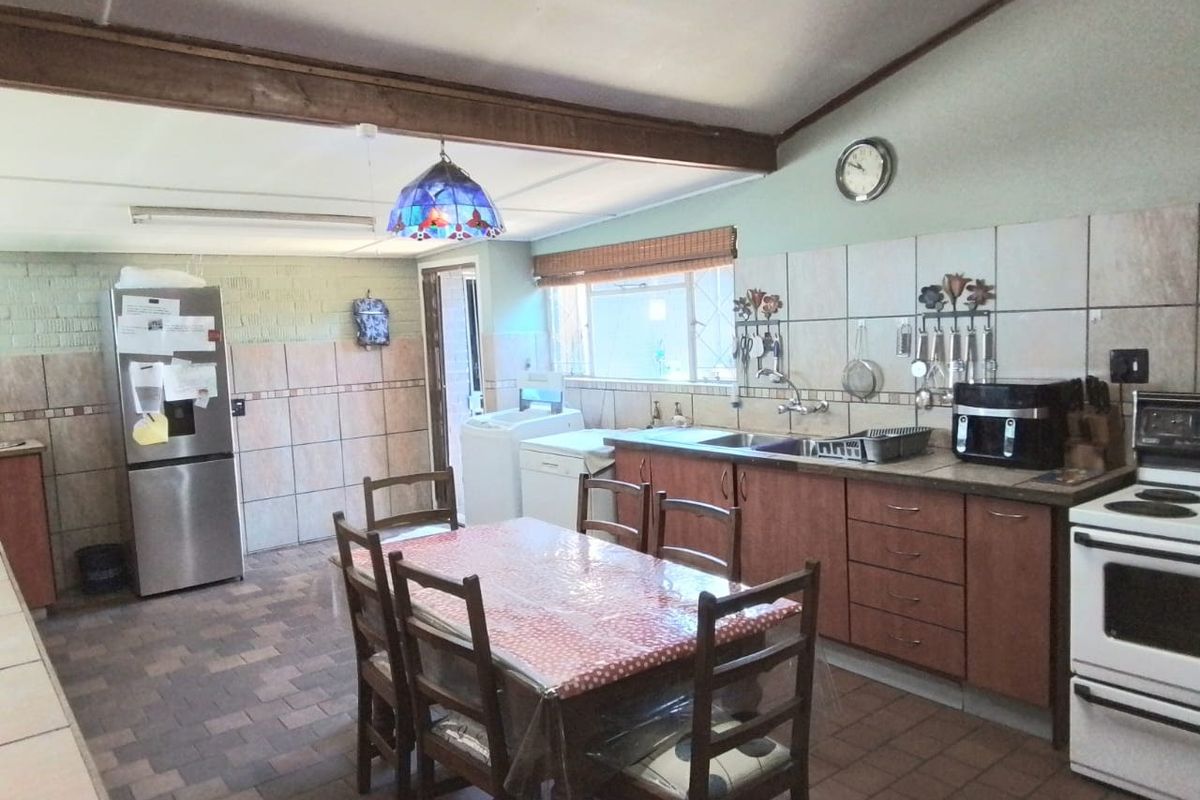 A functional kitchen featuring built-in cabinetry, a double sink, tiled backsplash, and a freestanding stove, with an exposed timber beam ceiling detail.