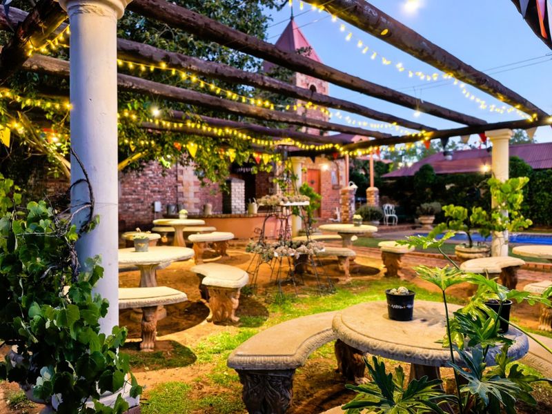 An outdoor entertainment area featuring a timber pergola, stone columns, and paved flooring, creating a charming space for gatherings.