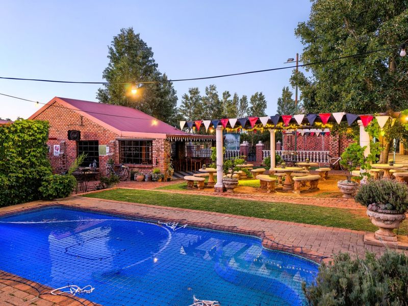 Outdoor entertainment area featuring a swimming pool with safety net, brick-paved patio, and a covered pergola structure.