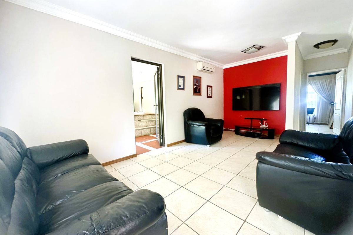 Spacious living room featuring neutral tiled flooring, a split-system air conditioner, and a bold red accent wall.