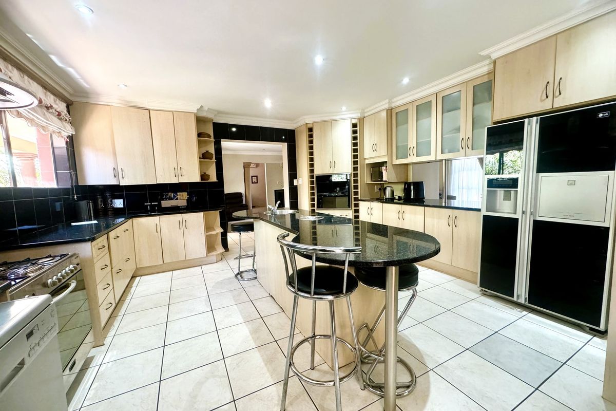 Spacious kitchen featuring light wood cabinetry, granite countertops, a central island, and tiled flooring, offering a functional layout for cooking and casual dining.
