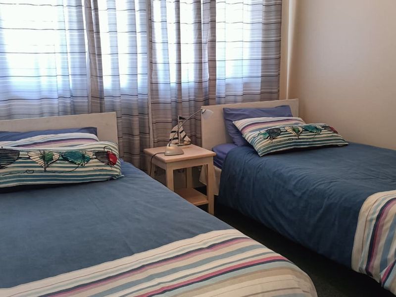 A functional bedroom featuring two single beds and window treatments, providing a comfortable sleeping space.