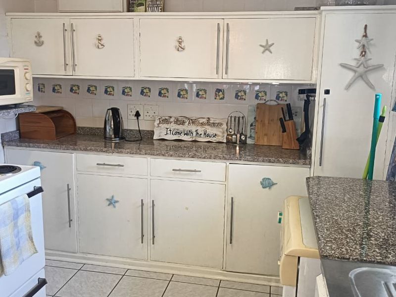 A functional kitchen featuring granite countertops, white cabinetry, tiled backsplash, and an electric stove, offering a practical layout for daily meal preparation.