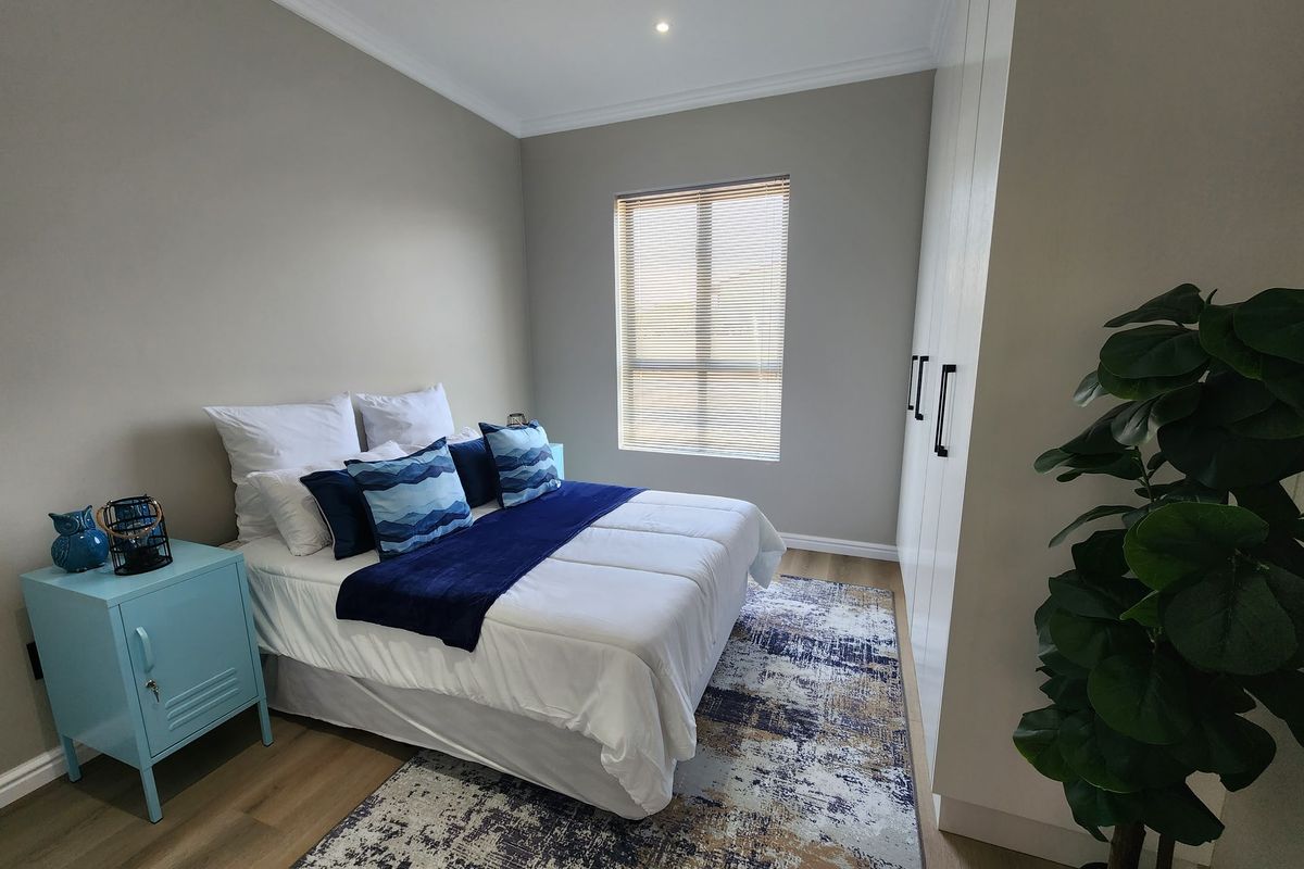 A well-maintained bedroom featuring neutral walls, laminate flooring, built-in cupboards, and modern recessed lighting.