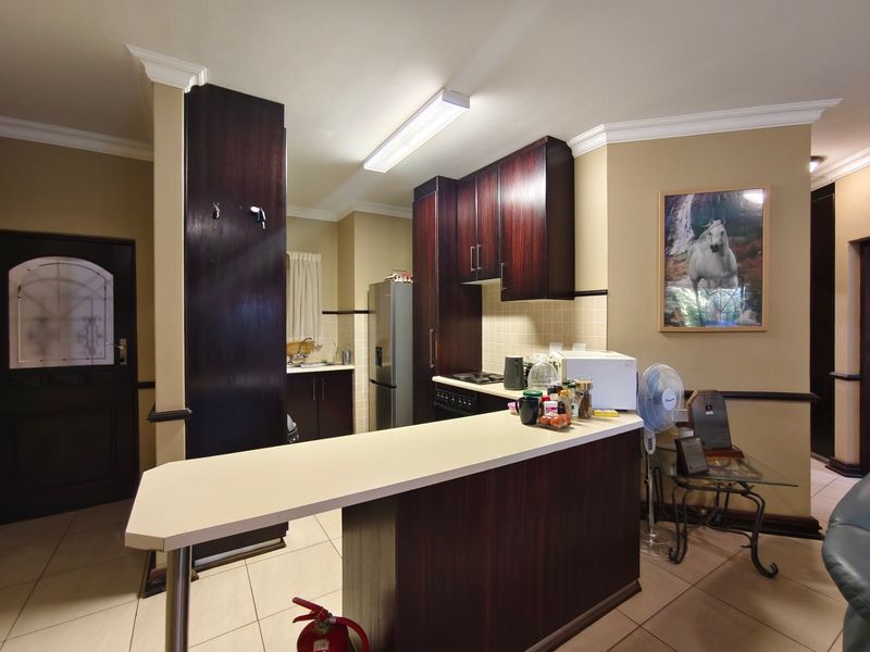 Open plan kitchen area featuring dark wood cabinetry, a breakfast bar, tiled flooring, and crown molding, providing a functional layout for daily living.