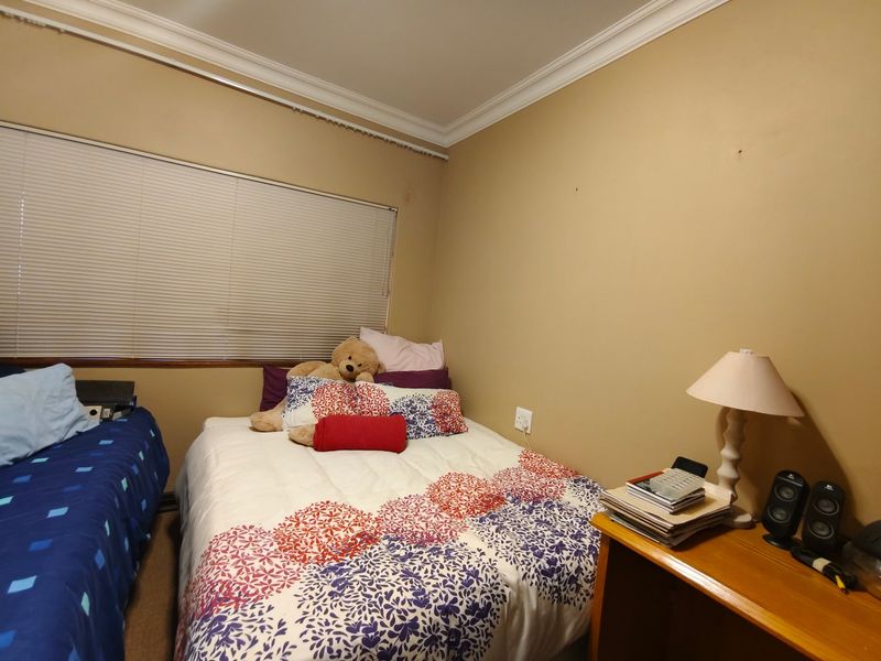 A standard bedroom featuring neutral wall paint, cornice detailing, and venetian blinds, providing a functional space ready for cosmetic updates.