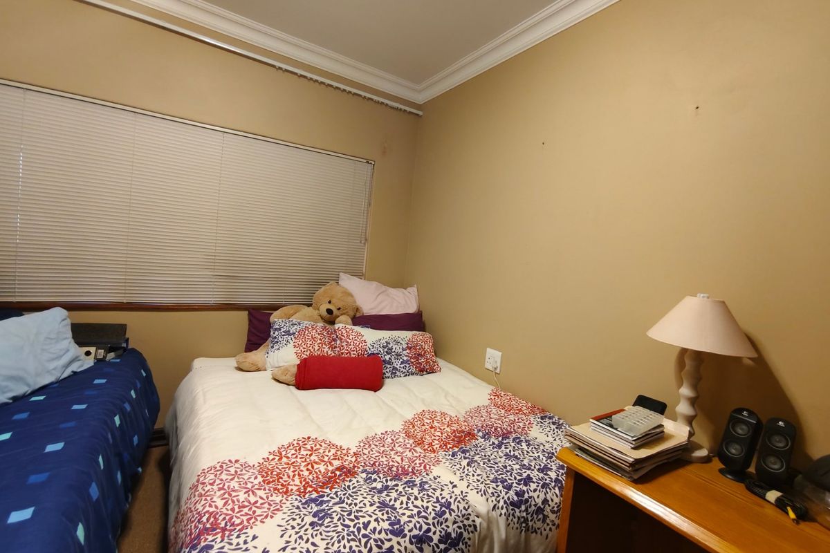 A standard bedroom featuring neutral wall paint, cornice detailing, and venetian blinds, providing a functional space ready for cosmetic updates.