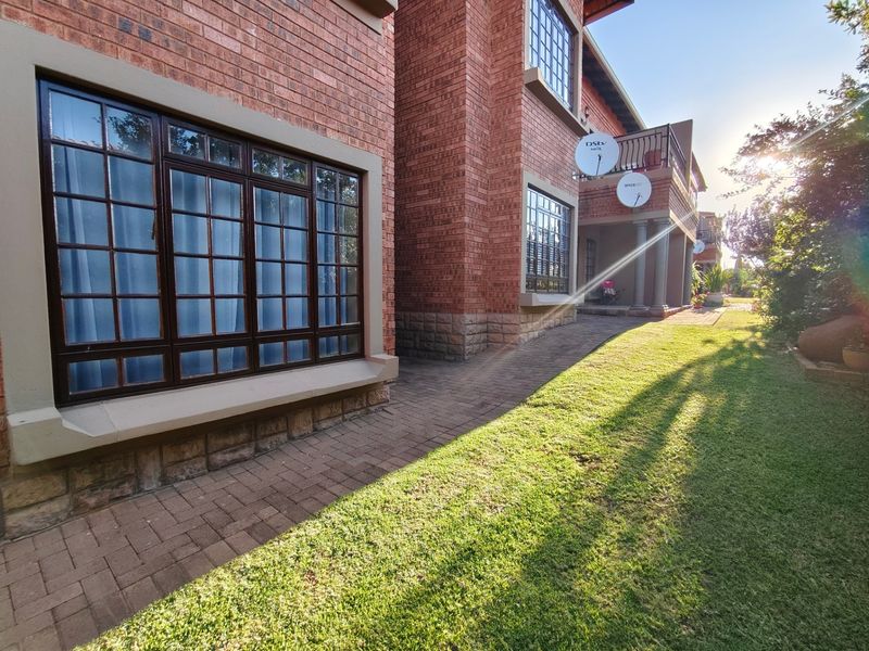Rear view of a face brick apartment building featuring a paved walkway, manicured lawn, and balcony access.