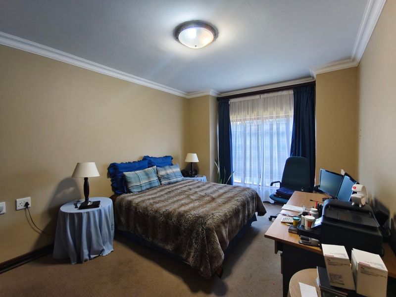 A functional bedroom featuring neutral wall tones, carpeted flooring, and decorative ceiling cornicing, providing a comfortable and well-lit living space.