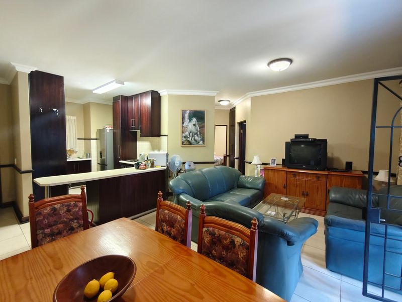 Open-plan living and kitchen area featuring dark wood cabinetry, a breakfast bar, and tiled flooring, offering a functional and connected living space.