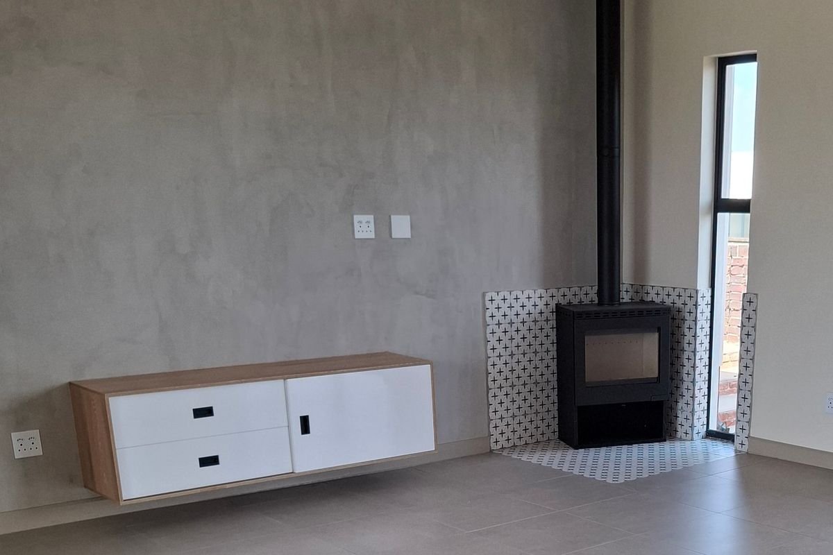 Modern living room featuring a sleek built-in fireplace with decorative tiling, floating cabinetry, and a wall-mounted air conditioning unit.