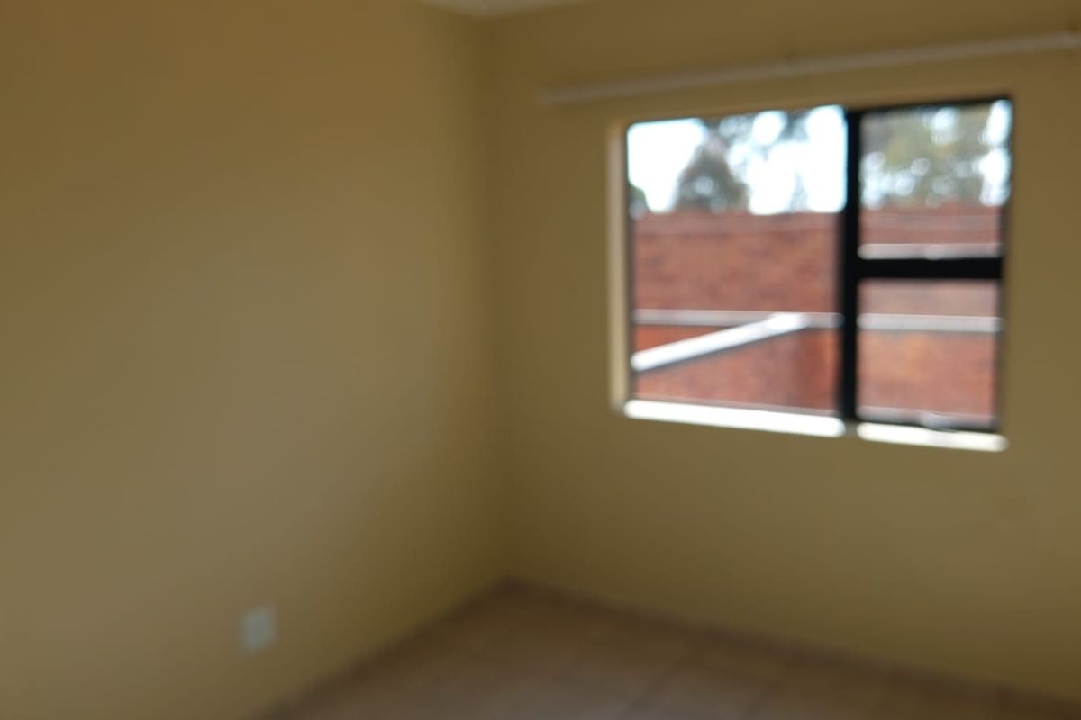 An empty bedroom featuring tiled flooring and an aluminium window frame, providing a blank canvas for personalization.