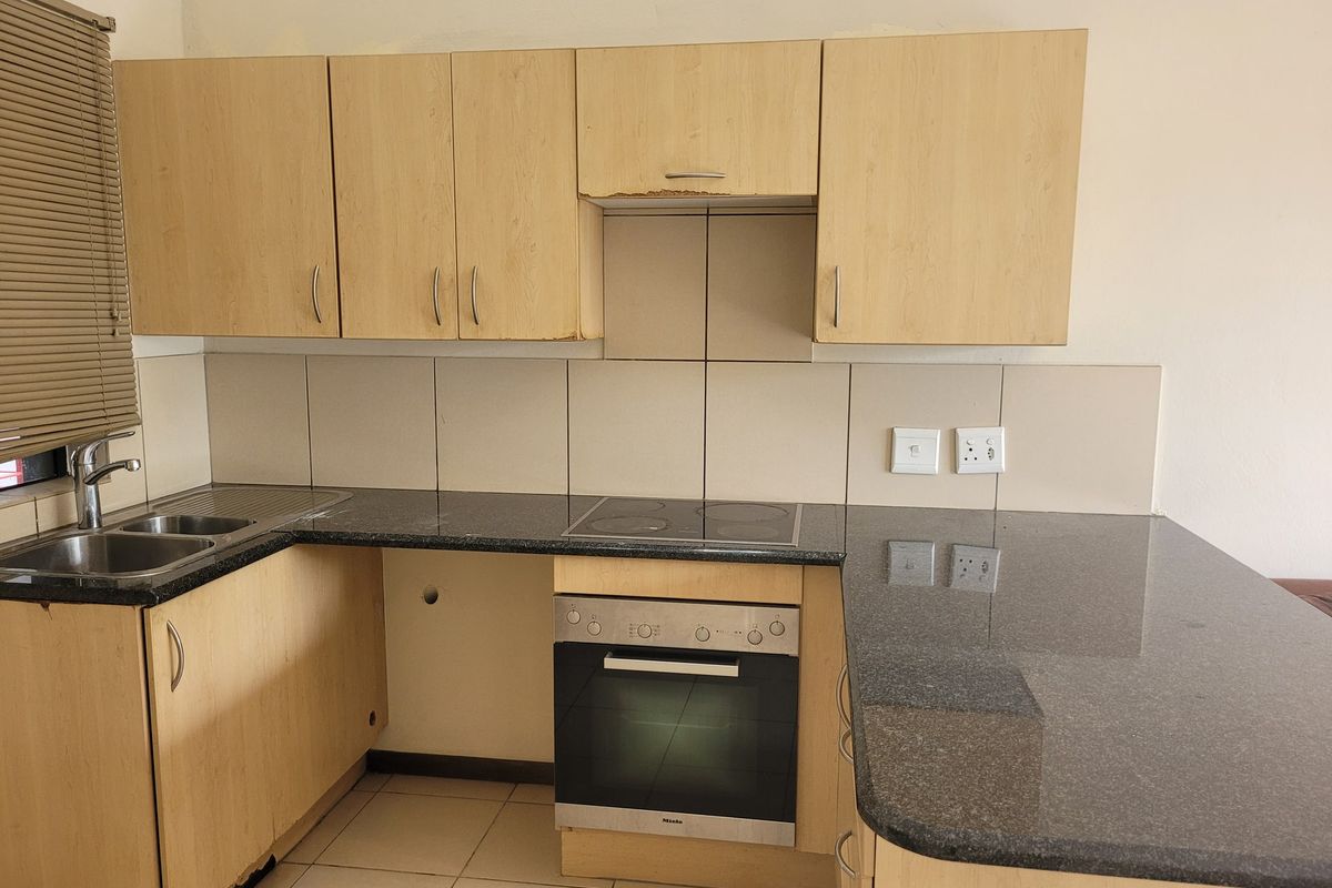 A functional kitchen featuring laminate cabinetry, granite countertops, a built-in oven, and an electric hob, ready for a modern update.