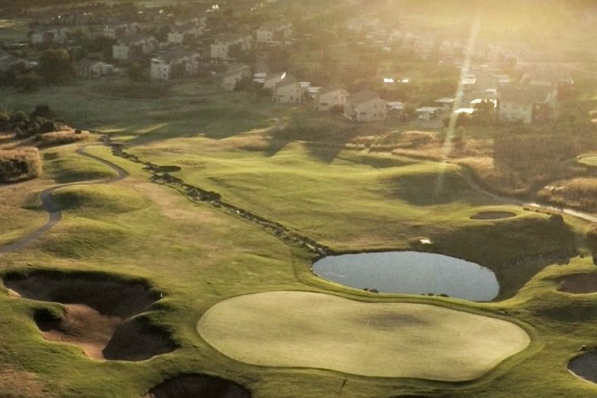 An aerial view of the surrounding golf course estate, showcasing landscaped greens, fairways, and water features in a scenic setting.