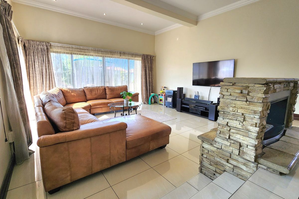 Spacious living room featuring large format tiled flooring, a prominent stone-clad fireplace, and expansive sliding glass doors providing natural light.