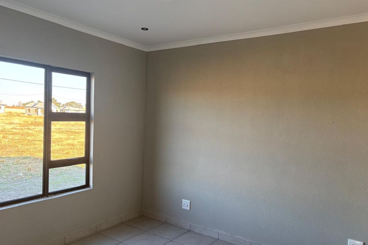 A clean, empty bedroom featuring neutral wall paint, tiled flooring, and recessed downlights, offering a blank canvas for personalization.