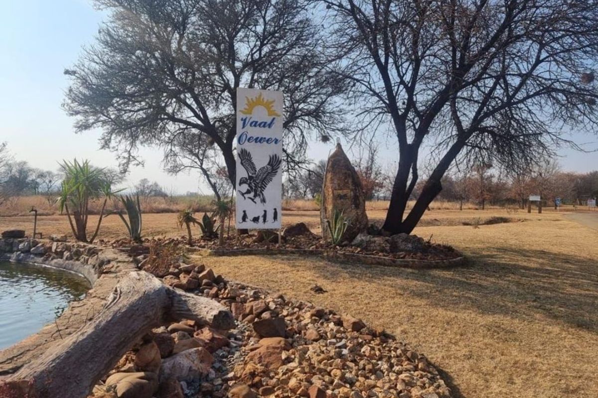 Entrance area of the Vaal Oewer property featuring a landscaped rock garden, water feature, and estate signage.