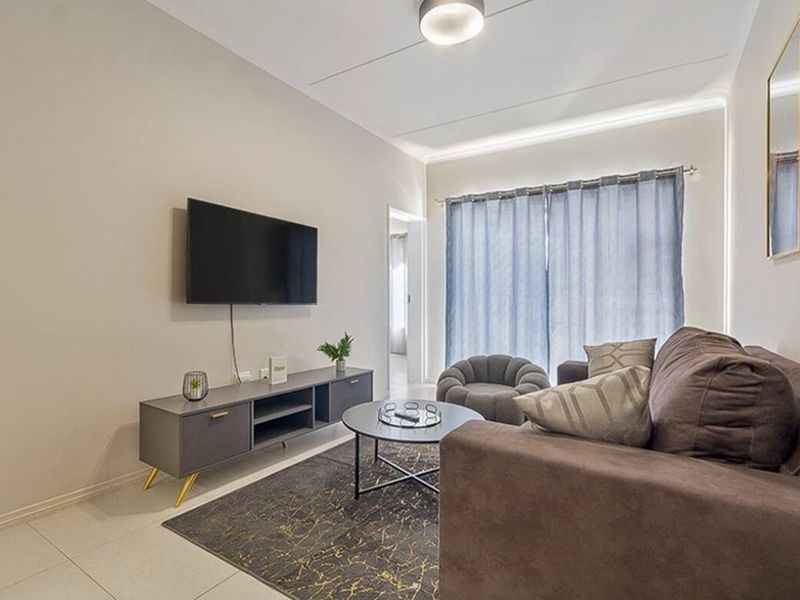A well-maintained living room featuring neutral walls, tiled flooring, and recessed ceiling lighting, providing a clean and functional space.