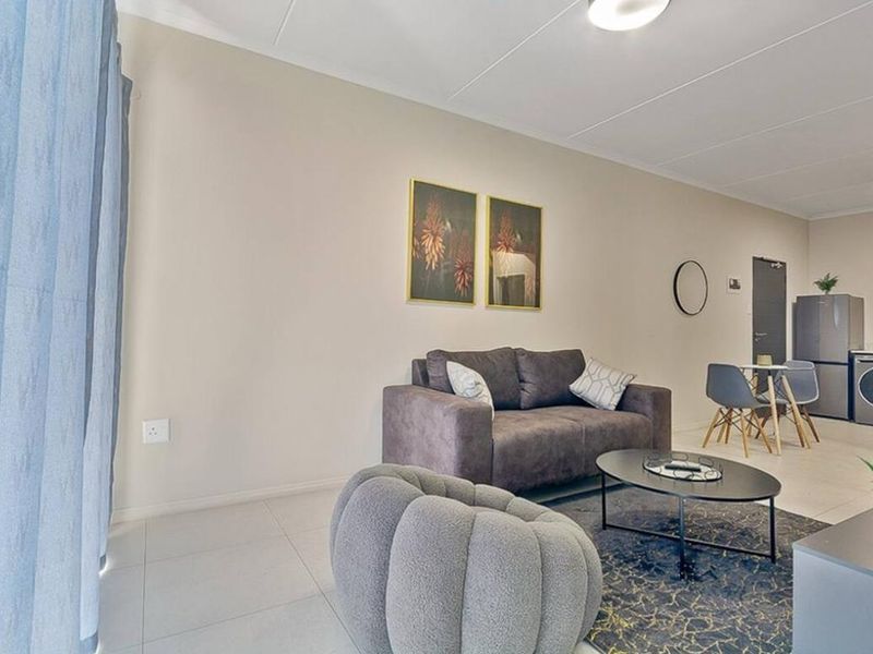 An open-plan living area featuring neutral wall tones and tiled flooring, creating a bright and functional space for relaxation and dining.