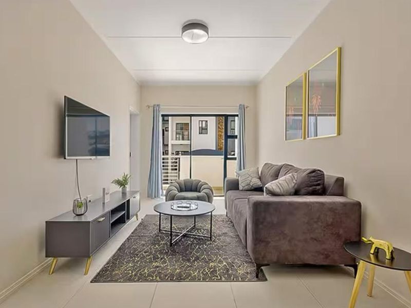 A well-maintained living room featuring tiled flooring and a sliding glass door that provides access to an outdoor balcony area.