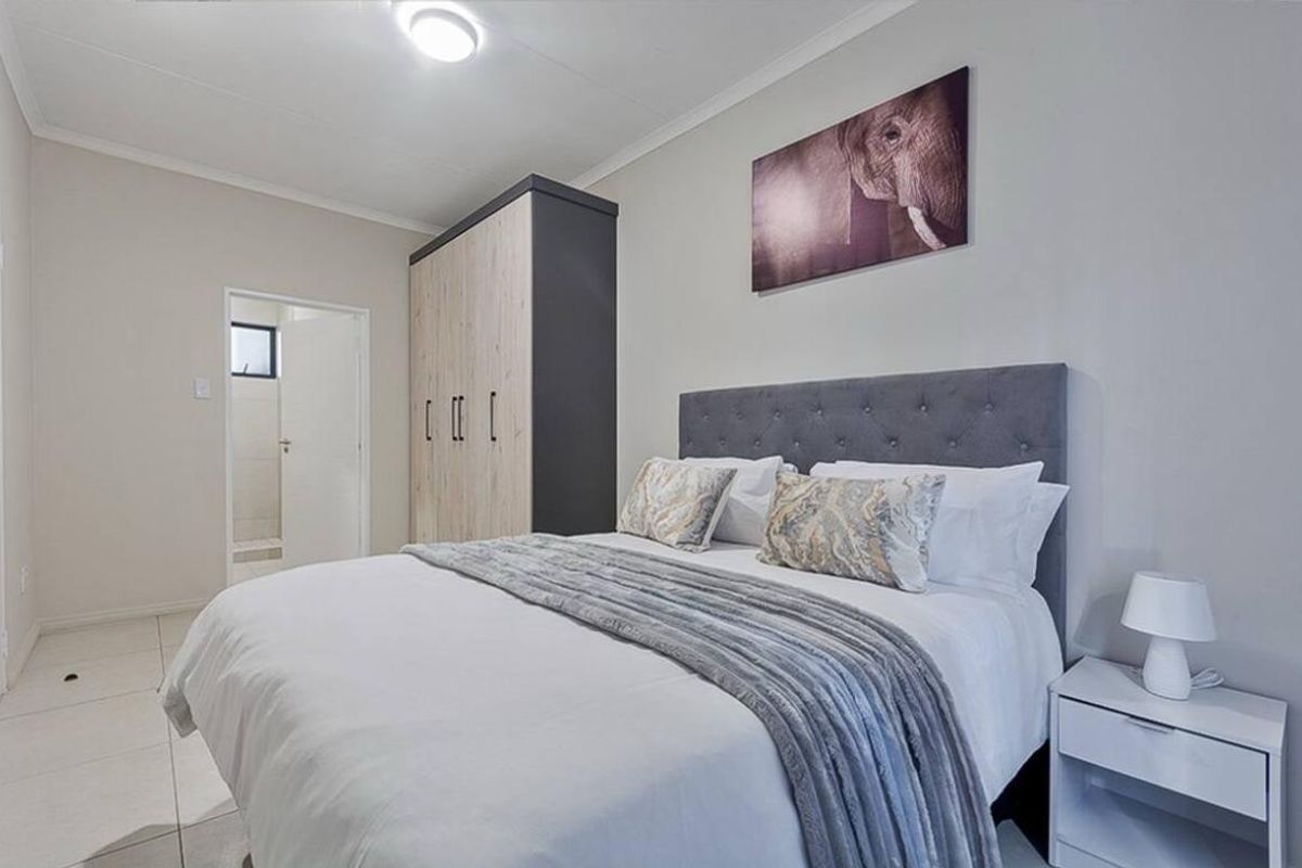 A well-maintained bedroom featuring tiled flooring, a built-in wardrobe, and direct access to an en-suite bathroom.