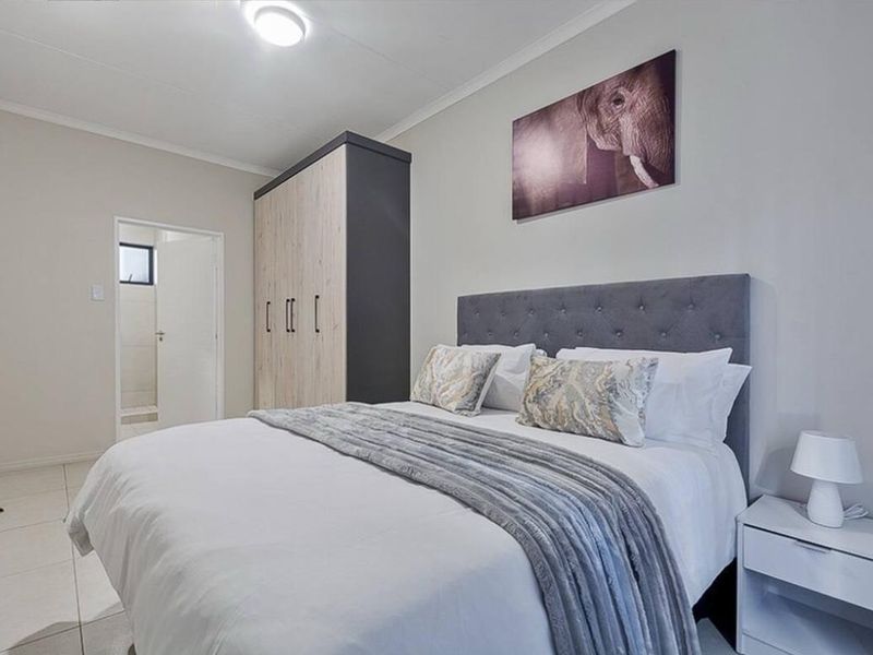 A well-maintained bedroom featuring tiled flooring, a built-in wardrobe, and direct access to an en-suite bathroom.