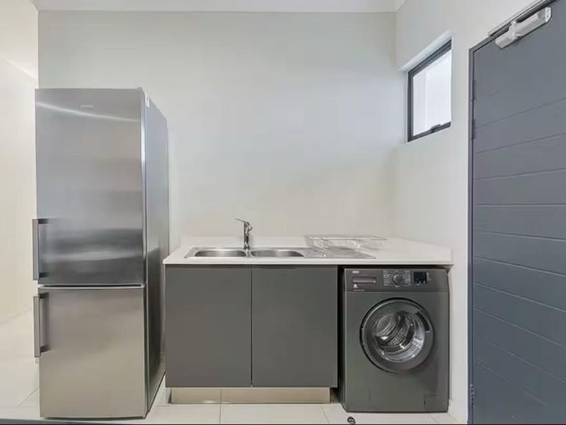 A clean and functional laundry area featuring built-in cabinetry, a double sink with mixer tap, and tiled flooring.