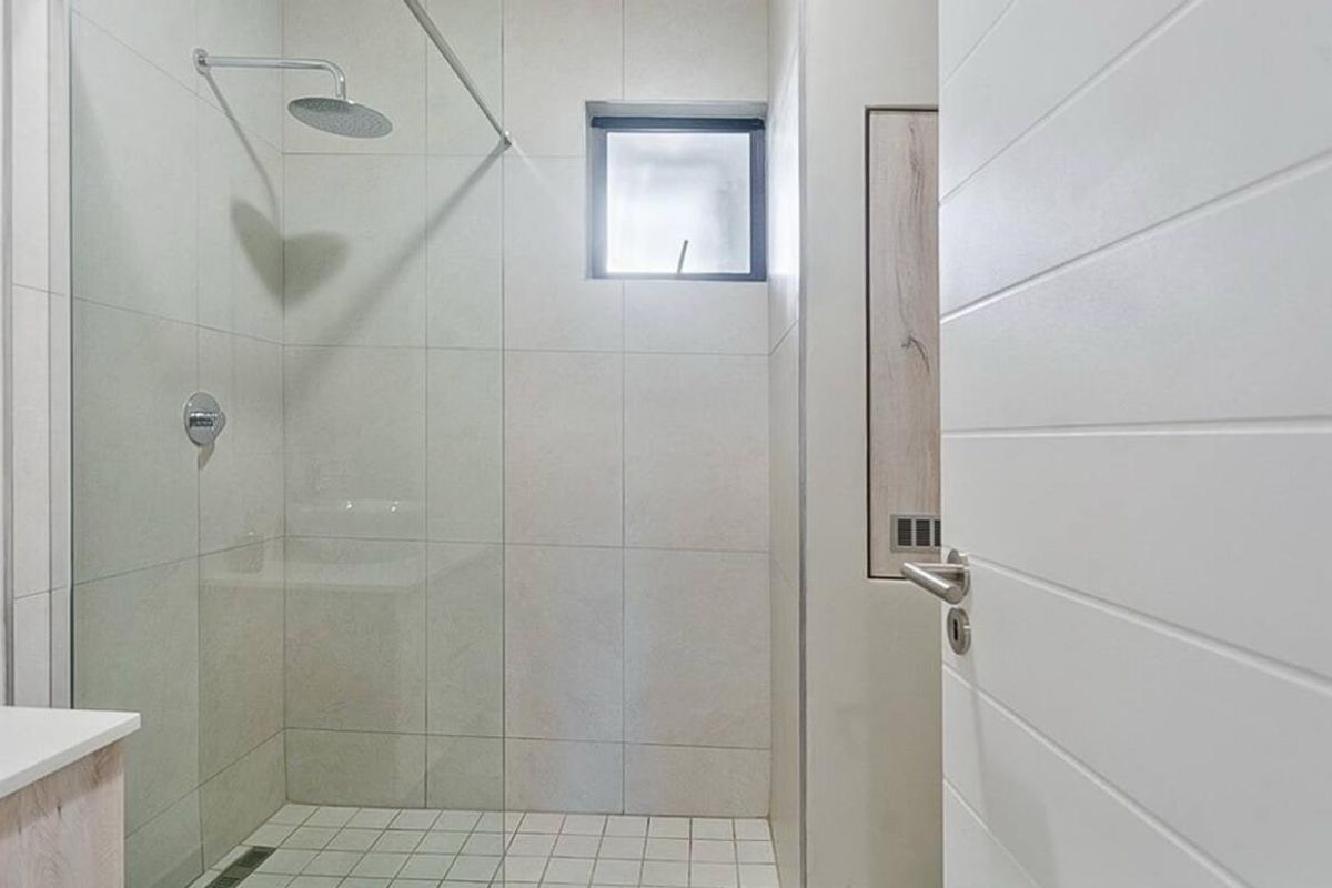 Modern bathroom featuring a walk-in shower with a rain shower head, glass screen, and neutral tiled finishes.