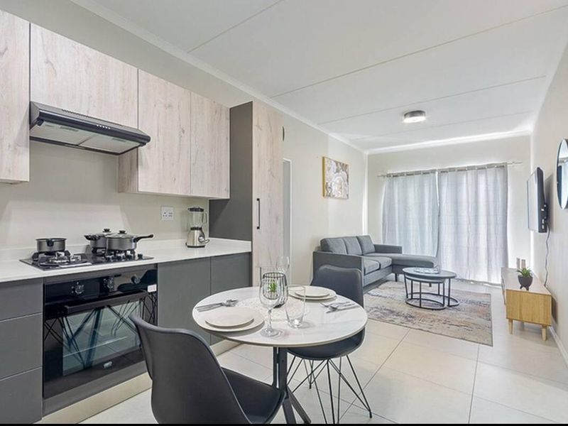 Modern open-plan living area featuring a contemporary kitchen with built-in appliances, tiled flooring, and seamless access to the patio through sliding glass doors.