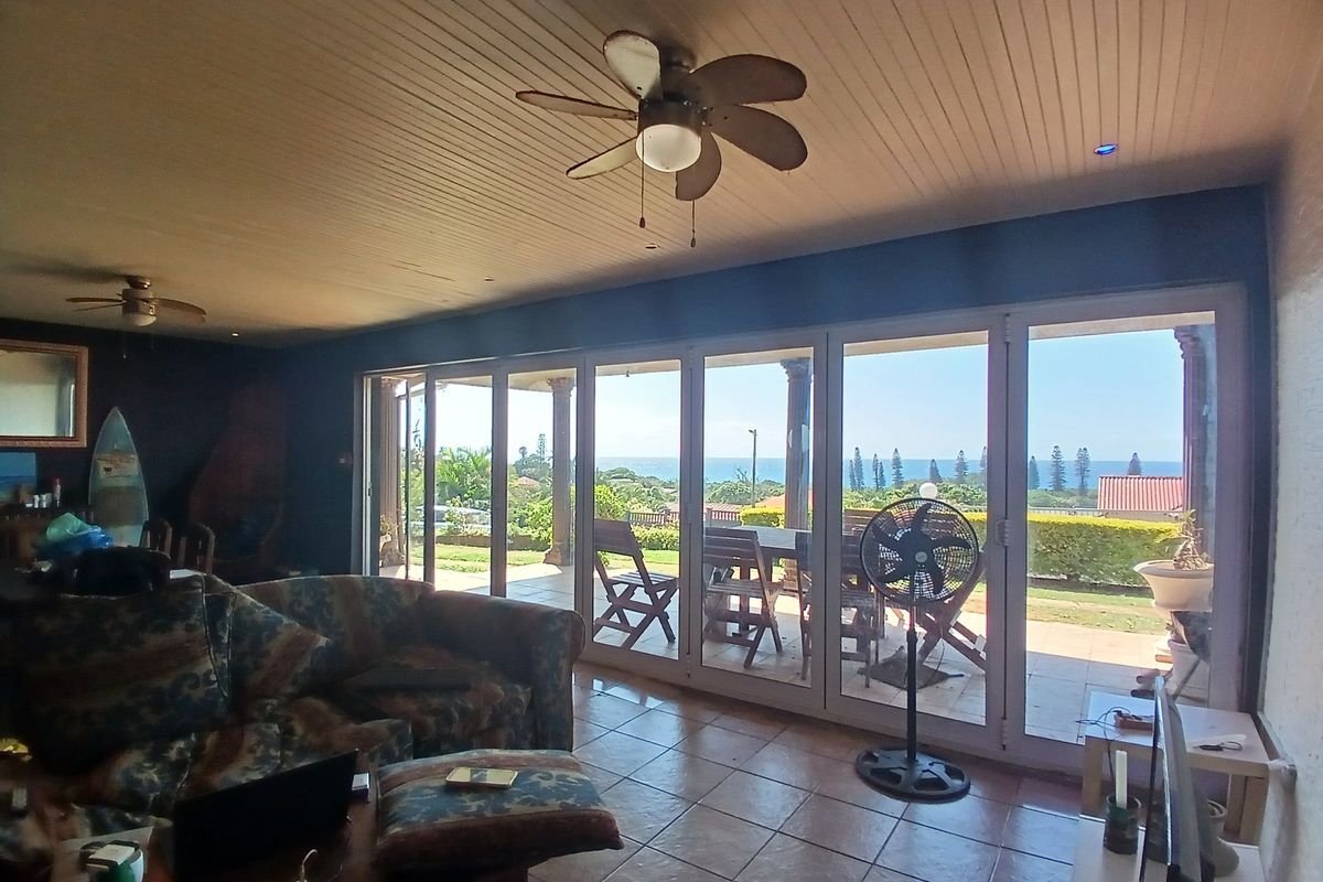 Spacious living room featuring tiled floors, a tongue and groove ceiling with fans, and large sliding glass doors opening to a scenic outdoor patio.
