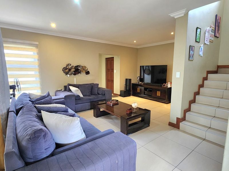 Spacious open-plan living area featuring tiled flooring, recessed lighting, and a staircase leading to the upper level.