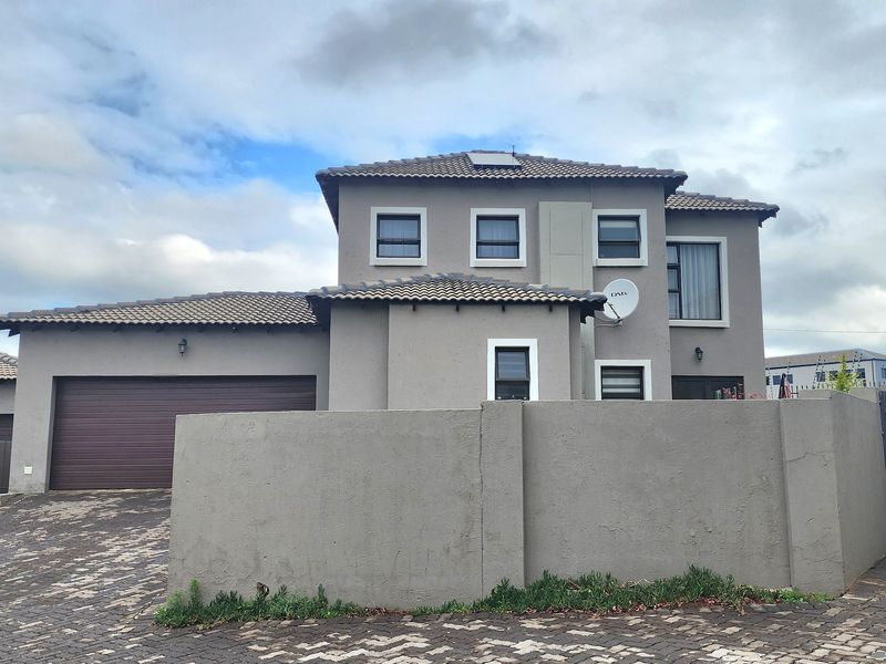 Front elevation of a double-storey residential house featuring a paved driveway, double garage, and a solid boundary wall.