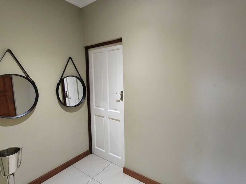 A clean and neutral hallway featuring tiled flooring, white internal door, and simple wall finishes.