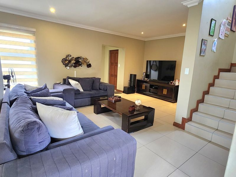 Spacious living room featuring tiled flooring, recessed lighting, and an integrated staircase, offering a comfortable and functional layout for family relaxation.