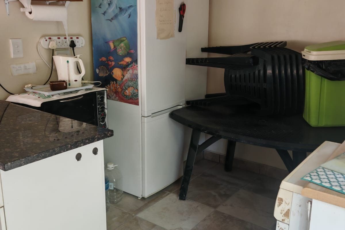 A compact kitchen area featuring granite countertops and tiled flooring, currently showing signs of wear and requiring cosmetic updates.