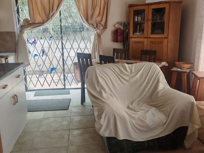 Open plan living and kitchen area featuring tiled flooring and a sliding glass door with security gate leading to the exterior.