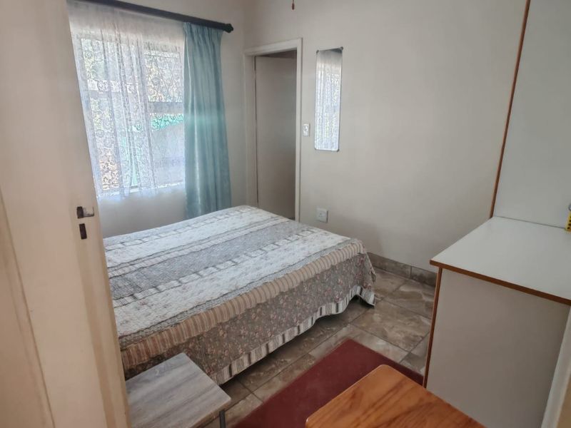 A functional bedroom featuring tiled flooring, a ceiling fan, and a built-in cupboard, offering a practical layout for a townhouse setting.