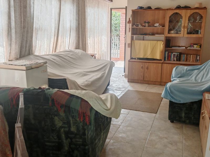 A living room featuring tiled flooring, a vaulted ceiling, and built-in cabinetry, with direct access to an outdoor area.
