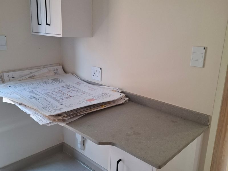 A clean, modern utility space featuring built-in cabinetry, a stone countertop, and tiled flooring, suitable for a home office or laundry prep area.