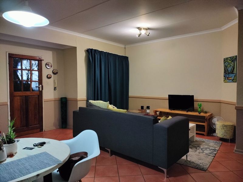 Open plan living area featuring tiled flooring, a timber entrance door, and coved ceilings, providing a functional and versatile space.