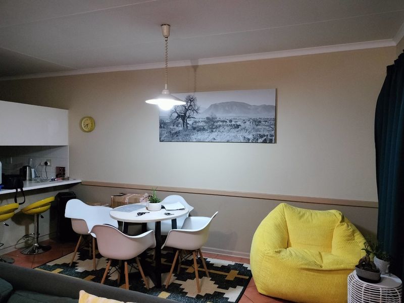 Open plan living and dining area featuring a breakfast bar, tiled flooring, and neutral wall tones, creating a functional and connected living space.
