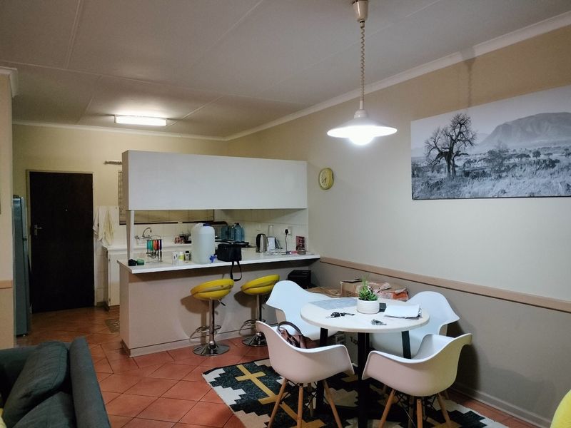 Open plan living and dining area featuring a breakfast bar, kitchen cabinetry with sink, and tiled flooring throughout.