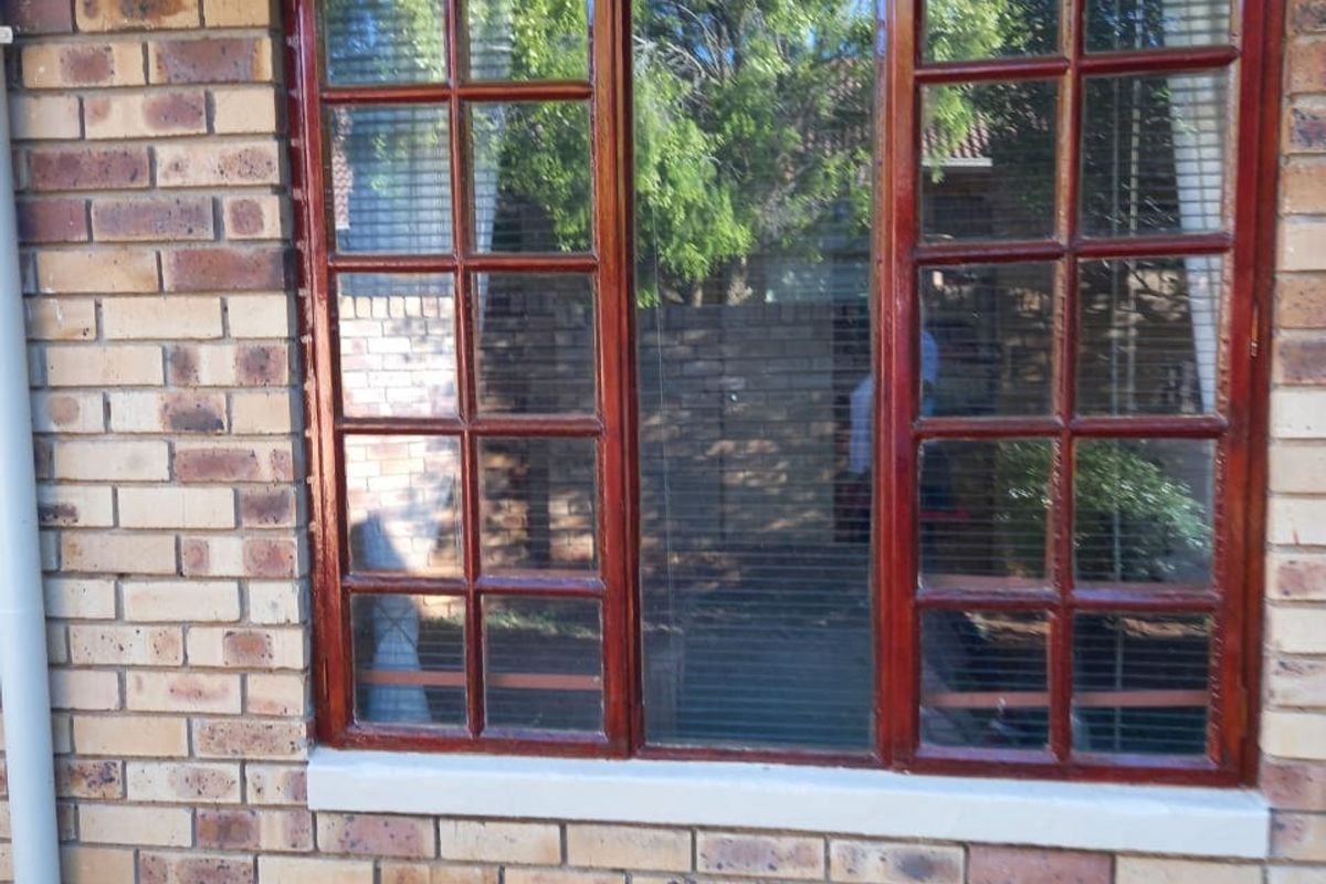 A view of the exterior rear face brick wall featuring a multi-pane timber frame window and a vertical downpipe.