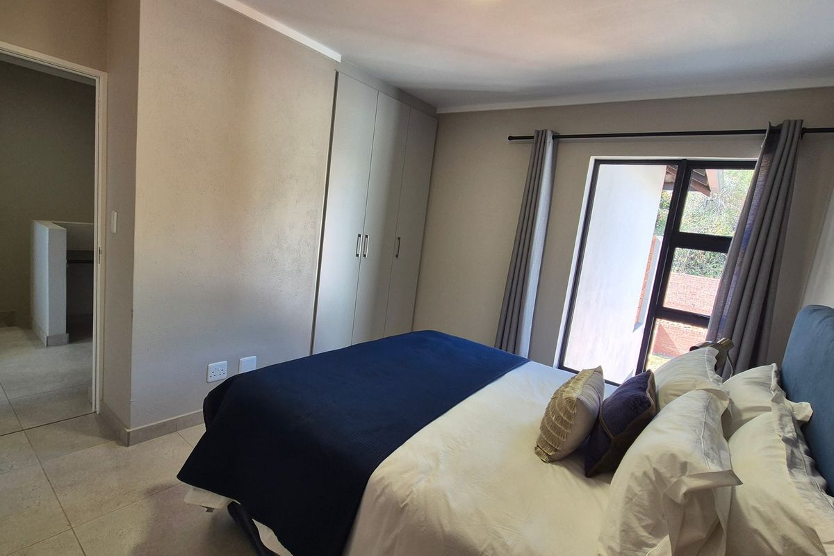A well-maintained bedroom featuring neutral walls, tiled flooring, and built-in cupboards with access to an adjoining hallway.