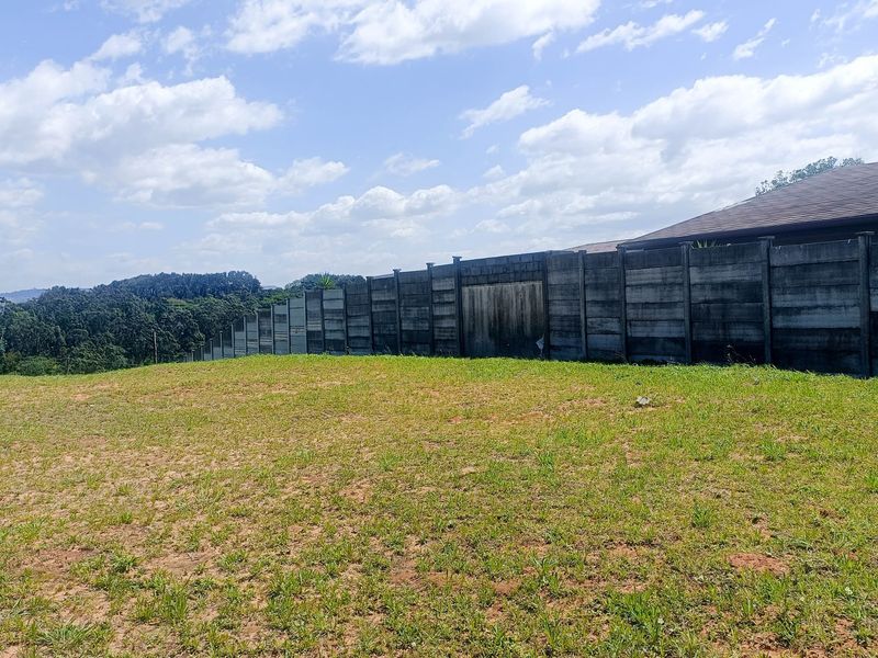 A vacant residential plot featuring a precast concrete boundary wall and expansive views of the surrounding landscape.