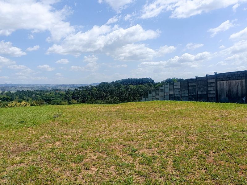 A vacant residential plot featuring expansive landscape views and a precast concrete boundary wall along the perimeter.